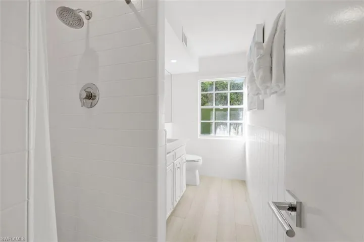 Bathroom featuring vanity, a shower stall, tile walls, and wainscoting