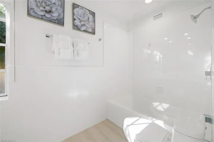 Full bath featuring tile walls, shower / bath combination, and a wainscoted wall