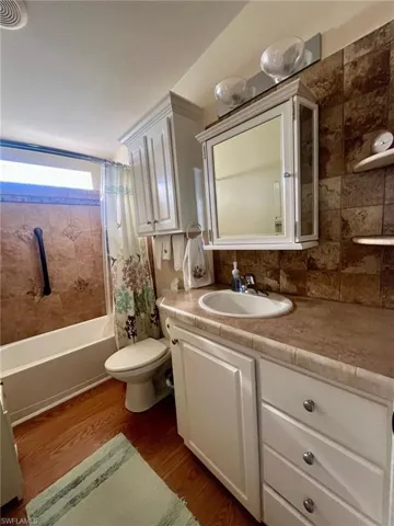 Full bathroom featuring vanity, dark wood-style flooring, and shower / bath combination with curtain