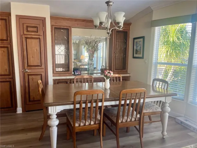 Dining area with a chandelier, wood finished floors, and ornamental molding