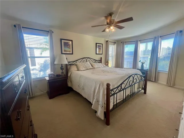 Bedroom with light colored carpet and a ceiling fan