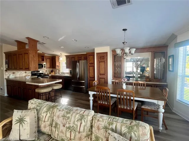 Dining space featuring a chandelier, dark wood-type flooring, and recessed lighting