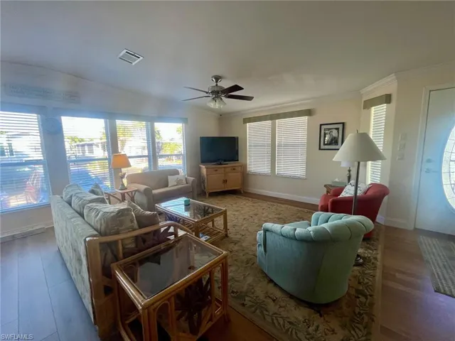Living room with wood finished floors, crown molding, and ceiling fan