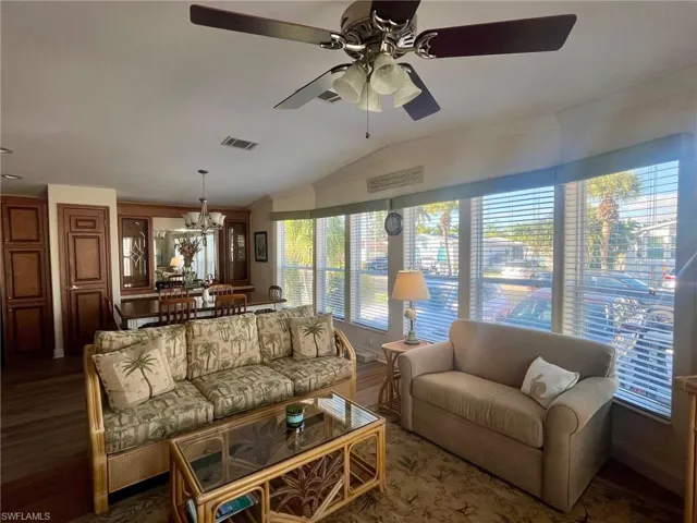 Living area with lofted ceiling, ornamental molding, a chandelier, wood finished floors, and ceiling fan
