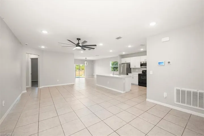Unfurnished living room with recessed lighting, a chandelier, light tile patterned flooring, and a ceiling fan
