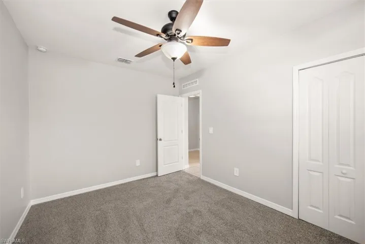 Unfurnished bedroom featuring carpet, ceiling fan, and a closet