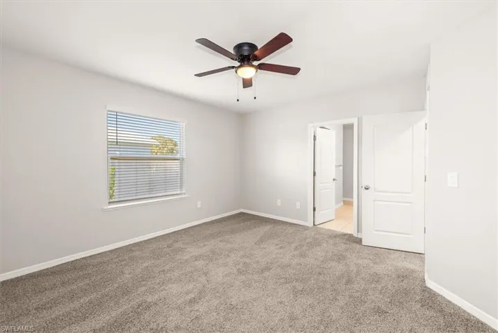 Unfurnished room featuring light carpet and a ceiling fan
