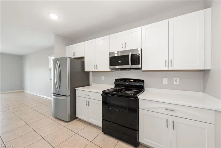 Kitchen with appliances with stainless steel finishes, white cabinets, light countertops, light tile patterned floors, and recessed lighting