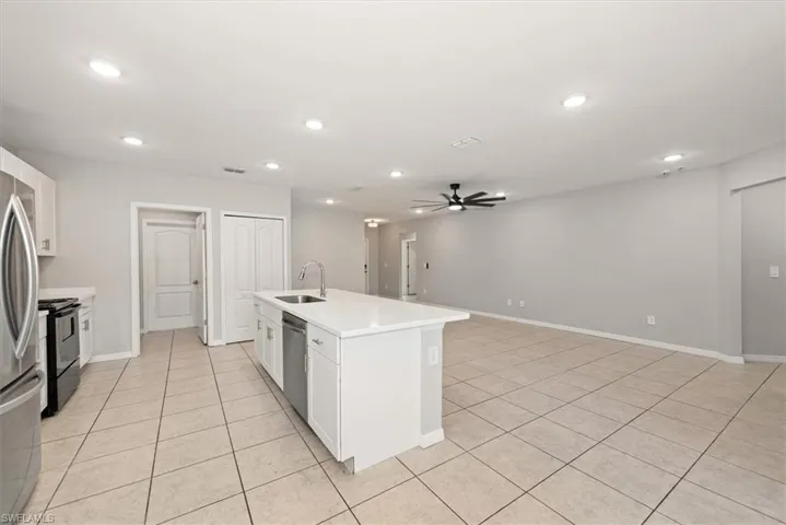 Kitchen featuring white cabinetry, an island with sink, appliances with stainless steel finishes, ceiling fan, and open floor plan