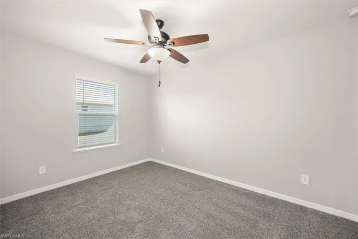 Carpeted spare room featuring baseboards and ceiling fan