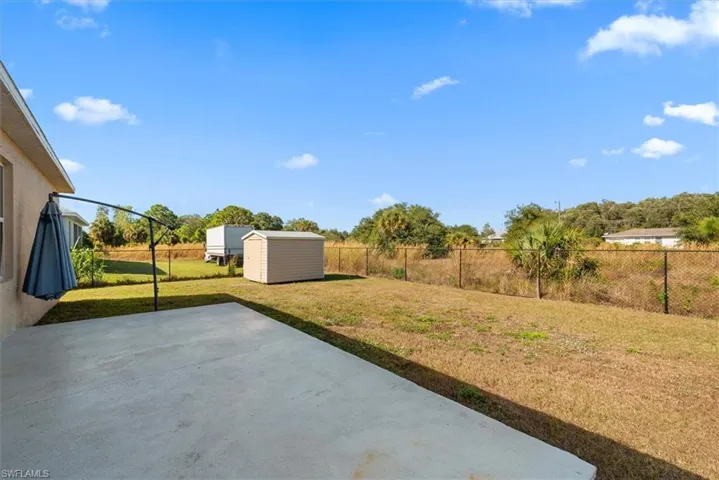 Fenced backyard featuring a shed and a patio area
