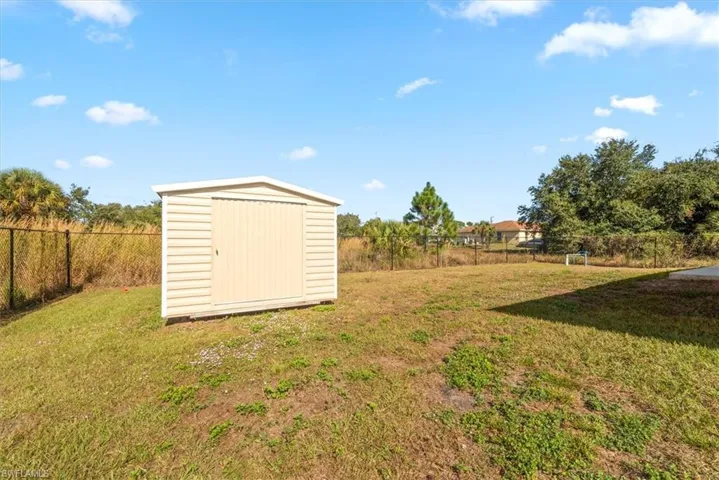Fenced backyard featuring a shed