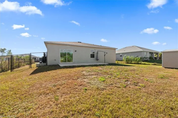 Rear view of property featuring a gate, a patio, and stucco siding