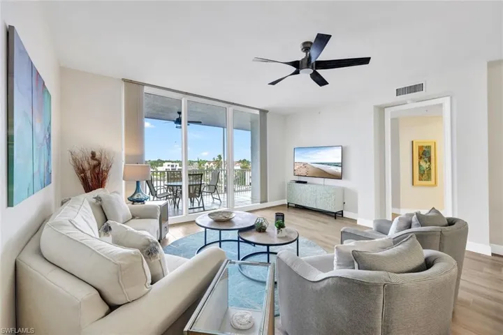 Living room with light wood-style floors, ceiling fan, and a wall of windows
