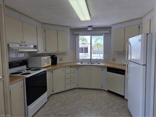Bright, cheerful kitchen with stove, fridge, microwave, & dishwasher.