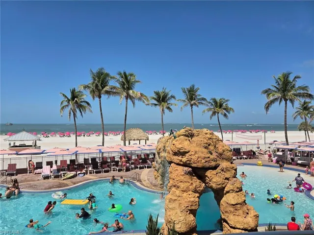 Community pool featuring view of water and beach