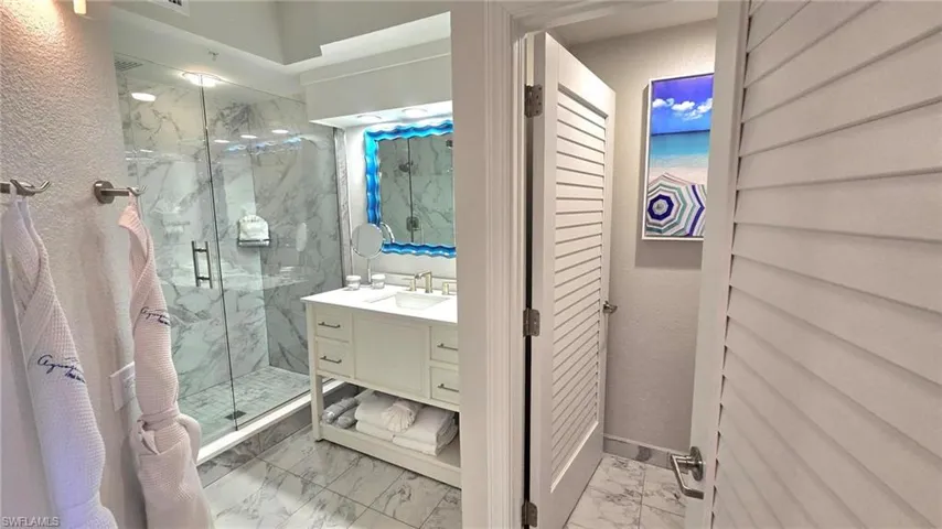 Full bathroom with marble look tile flooring, a marble finish shower, vanity, and a closet