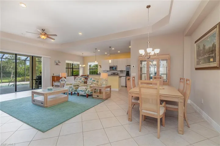 Tiled living room with a tray ceiling and ceiling fan with notable chandelier