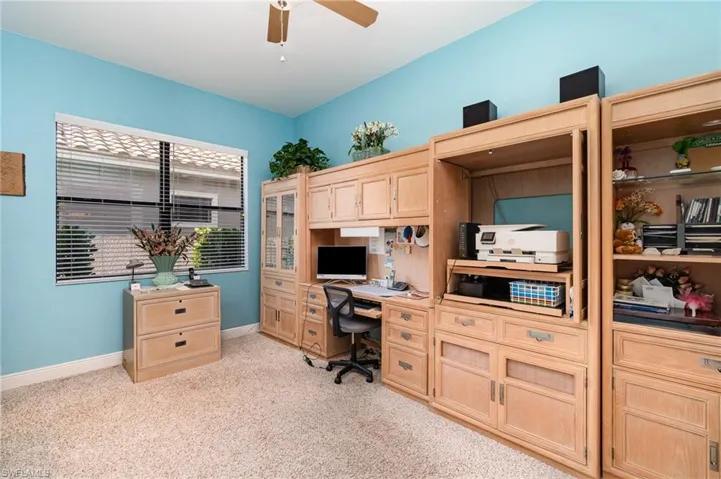 Carpeted home office featuring ceiling fan