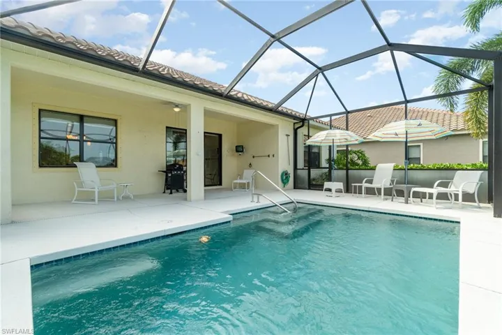 View of swimming pool with glass enclosure, a patio, and area for grilling