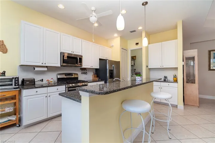 Kitchen with a center island, backsplash, white cabinetry, and appliances with stainless steel finishes