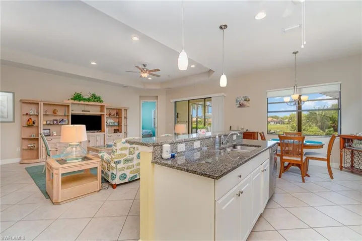 Kitchen with a wealth of natural light, sink, a tray ceiling, and ceiling fan with notable chandelier