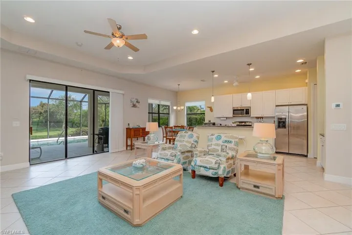 Tiled living room with ceiling fan and a raised ceiling