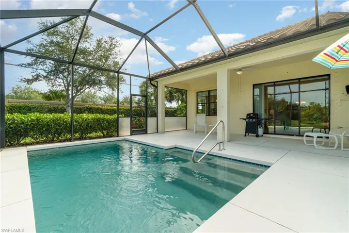 View of pool with glass enclosure, a patio area, and ceiling fan