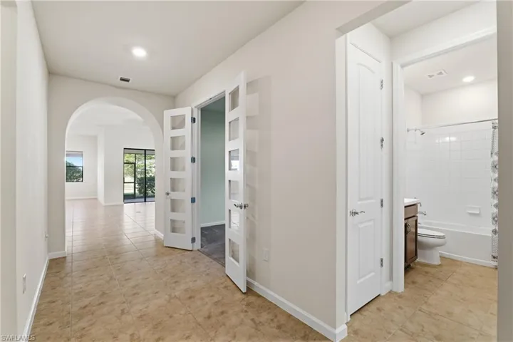 Entry viewing den with glass french doors and guest bathroom to the right