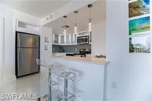 Kitchen with pendant lighting, white cabinets, a kitchen bar, stainless steel appliances, and glass insert cabinets