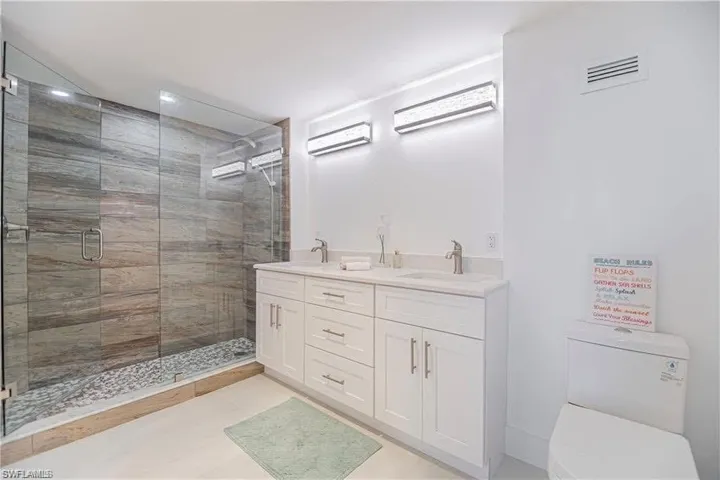 Full bath with double vanity and a shower stall