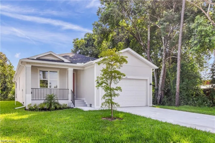 Ranch-style house featuring a garage, a front lawn, and covered porch