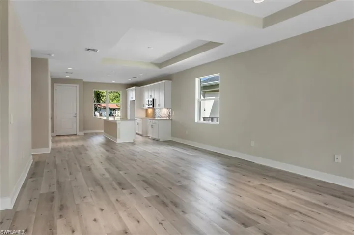 Unfurnished living room with light hardwood / wood-style floors and a tray ceiling