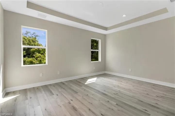 Spare room with light wood-type flooring and a raised ceiling
