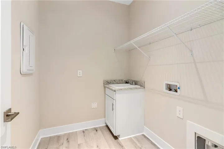 Laundry area with cabinets, washer hookup, sink, and light wood-type flooring
