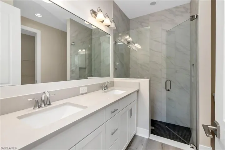 Bathroom with an enclosed shower, vanity, and hardwood / wood-style flooring
