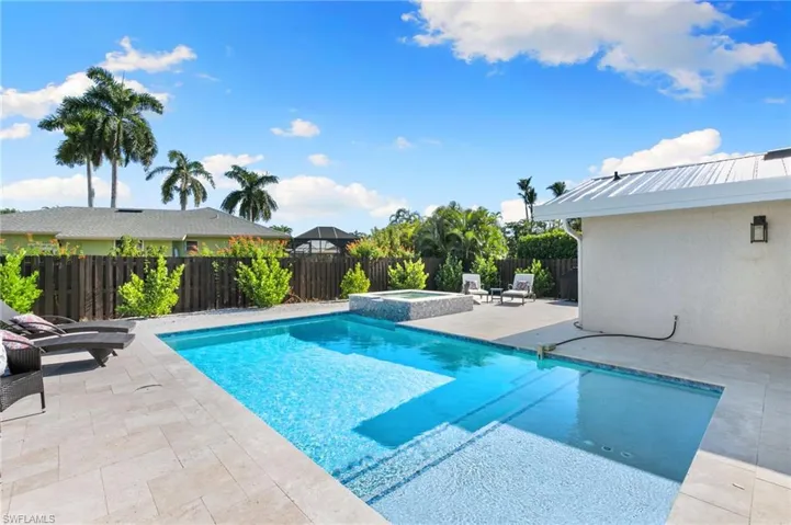 View of pool with a patio, a fenced backyard, and a pool with connected hot tub