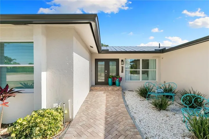 Entrance to property with stucco siding, a metal roof, and french doors