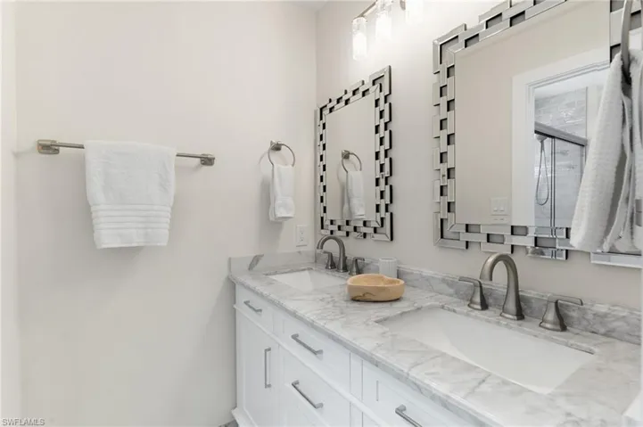 Full bath featuring double vanity and an enclosed shower