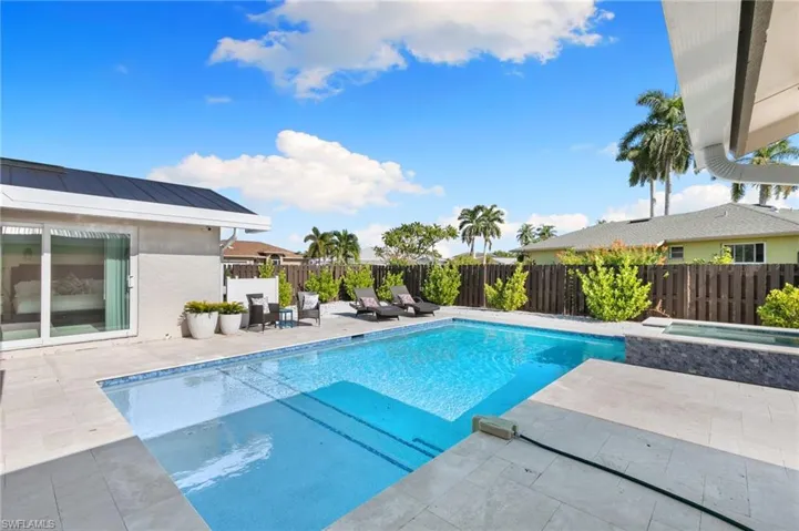 View of pool with a patio, a fenced backyard, and a pool with connected hot tub