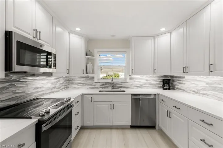 Kitchen with appliances with stainless steel finishes, white cabinetry, open shelves, decorative backsplash, and recessed lighting
