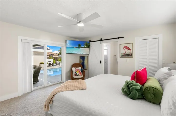 Bedroom featuring a barn door, carpet floors, access to exterior, a closet, and ceiling fan