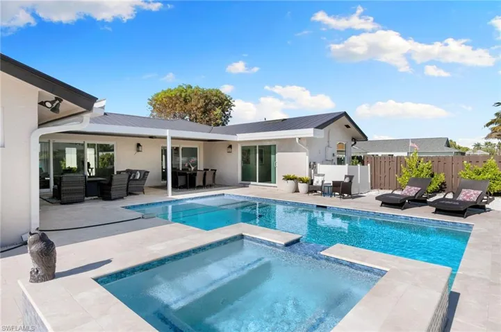 Rear view of house featuring an outdoor hangout area, a patio area, stucco siding, a pool with connected hot tub, and a metal roof