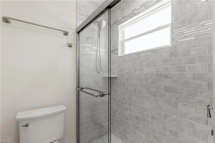 Full bathroom featuring a stall shower and toilet