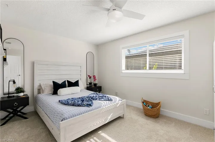 Bedroom with a textured ceiling, ceiling fan, and light colored carpet
