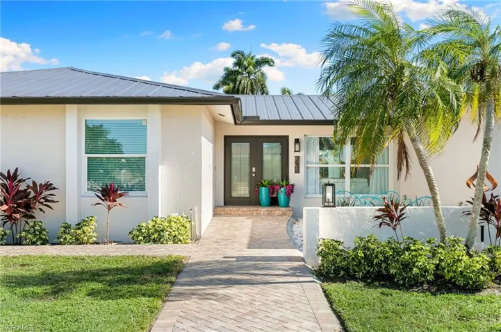 Doorway to property with stucco siding, a metal roof, and french doors
