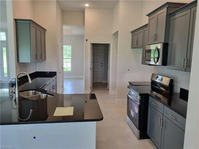 Kitchen with stainless steel appliances, sink, light tile patterned floors, and kitchen peninsula