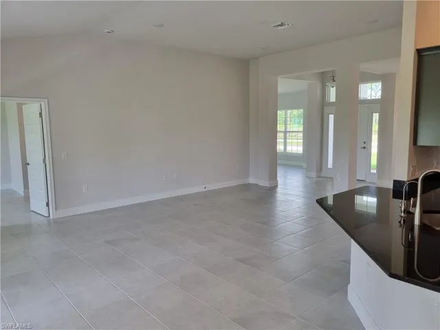 Unfurnished living room featuring vaulted ceiling and light tile patterned flooring