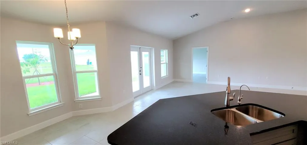 Kitchen with lofted ceiling, light tile patterned floors, plenty of natural light, and sink