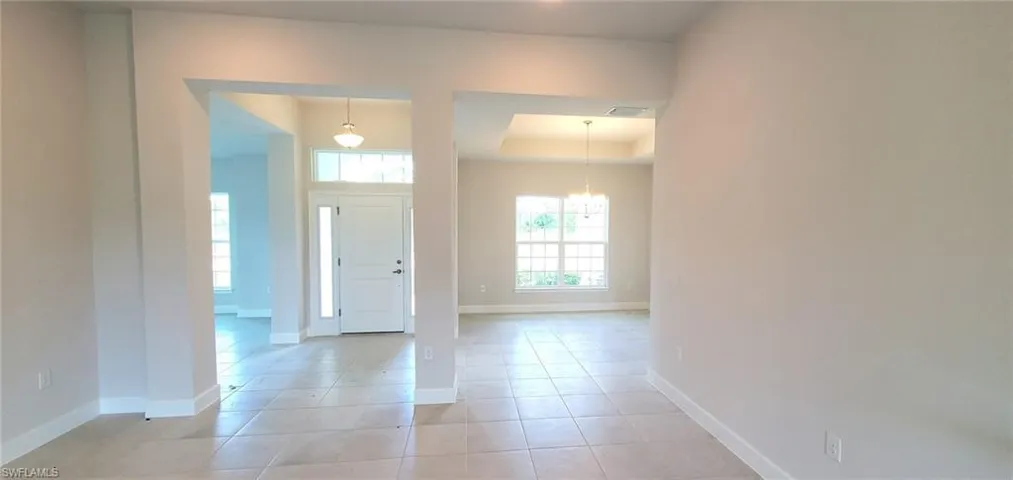 Tiled foyer entrance with a raised ceiling and an inviting chandelier